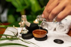 Aromatherapy massage setup with essential oil being poured, hot stones, and spa elements at Carval Health Spa in Business Bay.