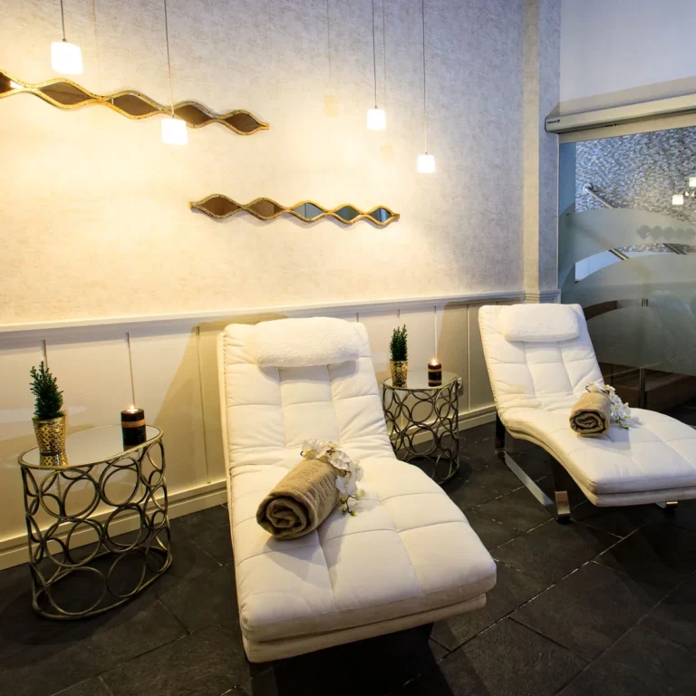 Elegant spa relaxation lounge with white recliners, rolled towels, and soft lighting at a wellness center in Business Bay.